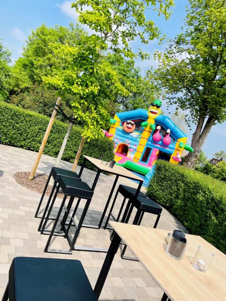 Een Sfeervol terras, met gezellige tafeltjes en een springkasteel.