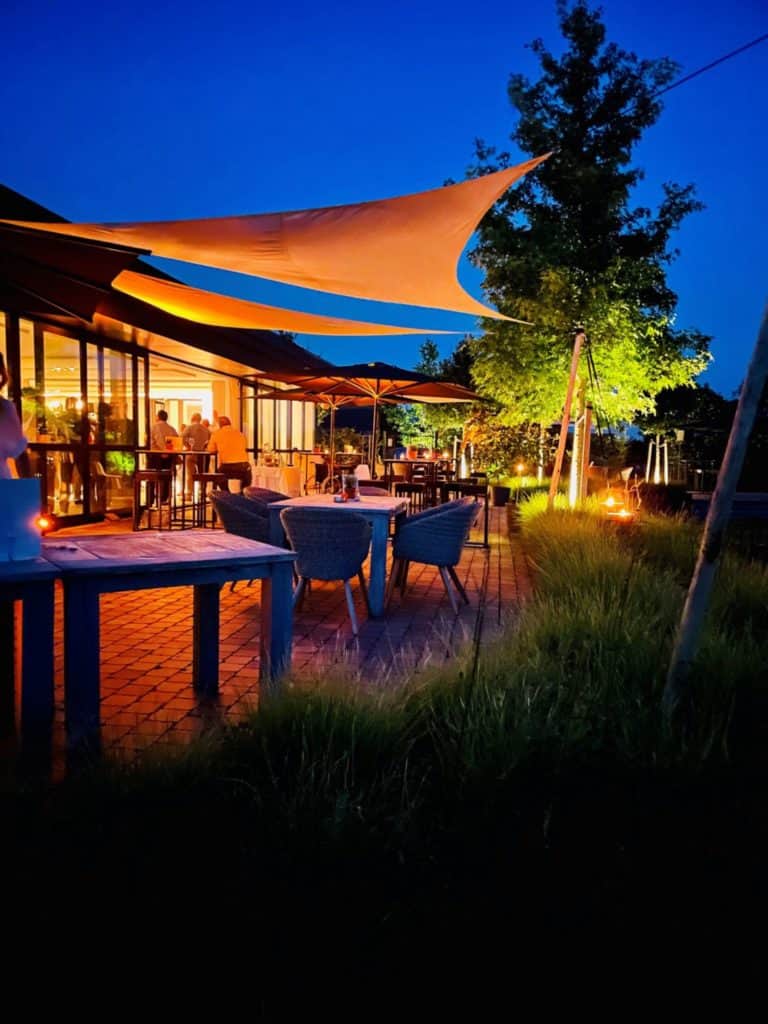 Onze feestzaal 's avonds buitentafels en stoelen, waardoor er een gezellige en sfeervolle ambiance ontstaat.