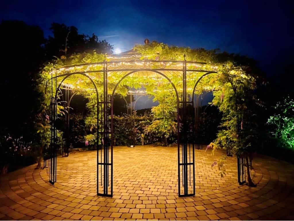 Een prachtig verlicht tuinpaviljoen dat 's avonds een magische sfeer creëert in de tuin.