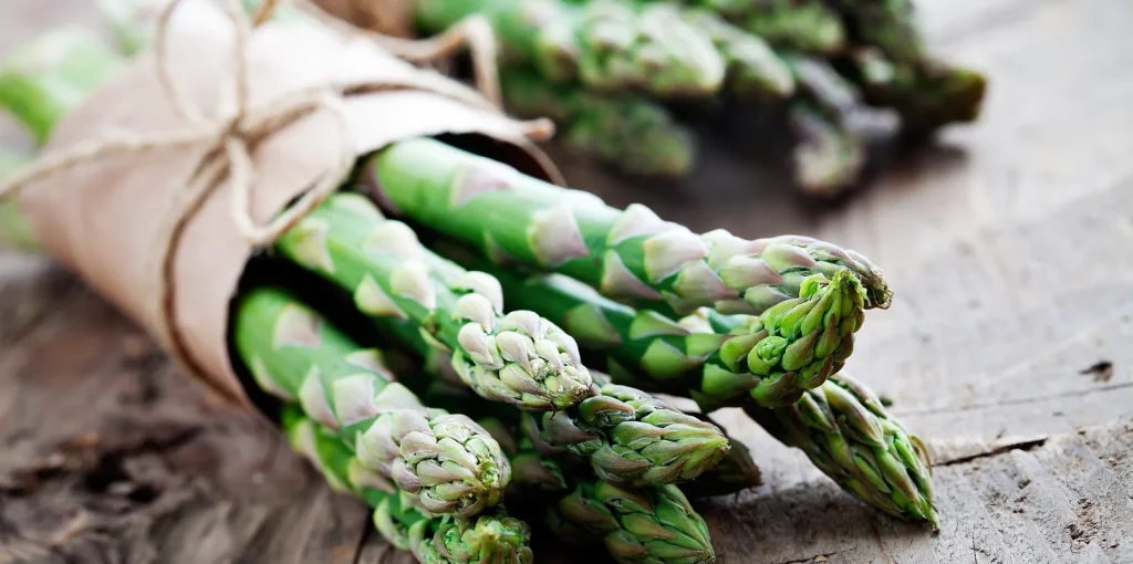 Verse groene asperges vastgebonden met touw op een rustiek houten oppervlak voor privéfeesten.
